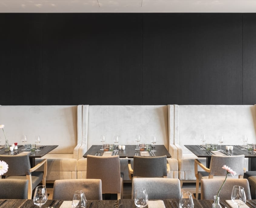 Nicely set tables with black wall panels in the restaurant of the Mercure Hotel